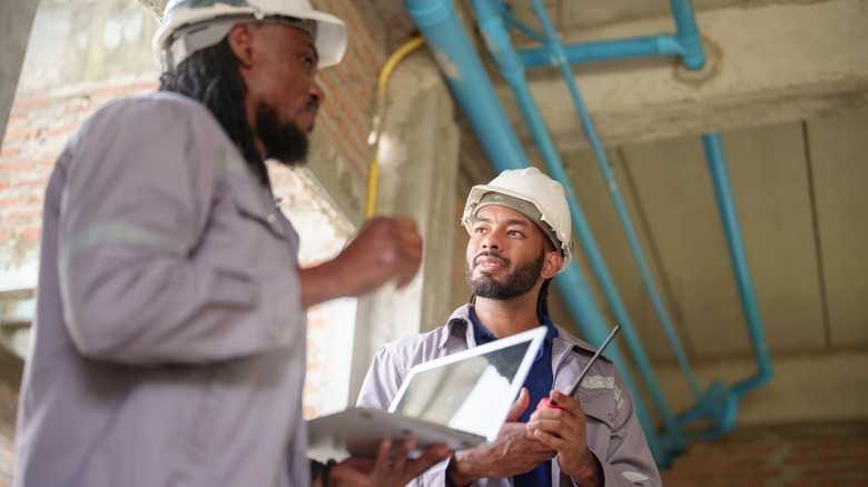 Two contractors on site, both in hard hats