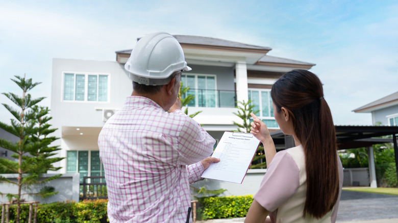 Inspector and home owner pointing at home exterior