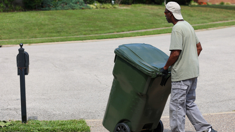 Man taking trash can to curb