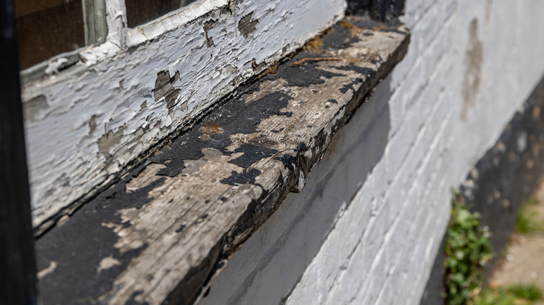 Old wooden window ledge with black peeling paint
