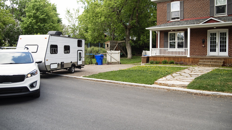 Car backing RV into suburban driveway