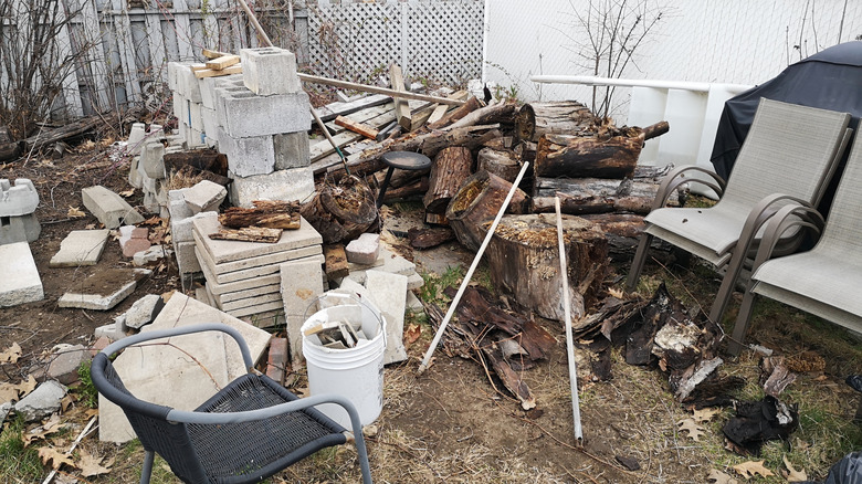 Yard full of bricks, logs, and old furniture