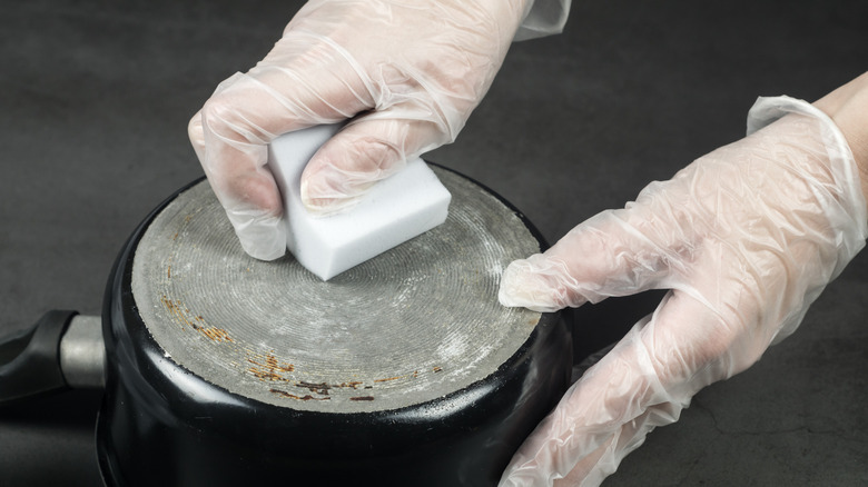 Gloved hand using a cleaning eraser on a pan