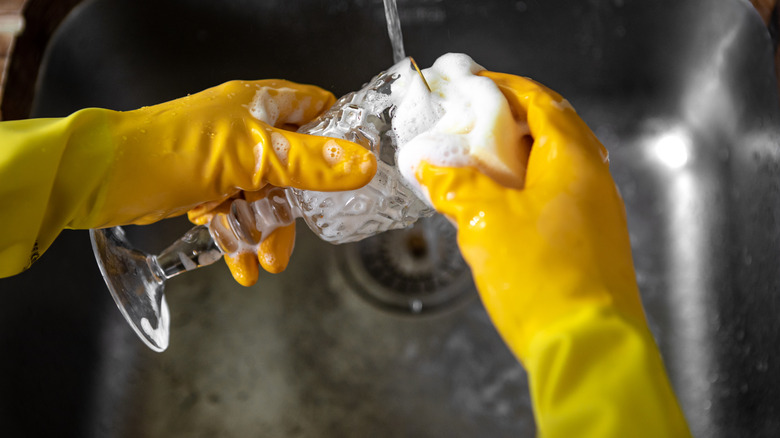 Closeup of a person wearing yellow gloves cleaning a glass