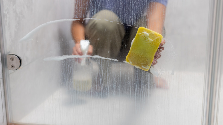 Woman wiping off hard water stains from shower door