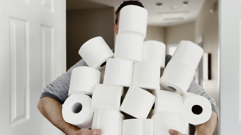 Man hidden behind stacks of toilet paper