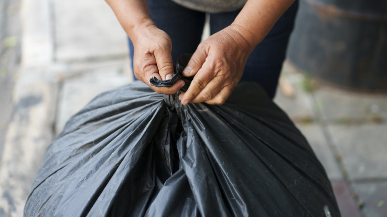 Closeup of person tying a trash bag