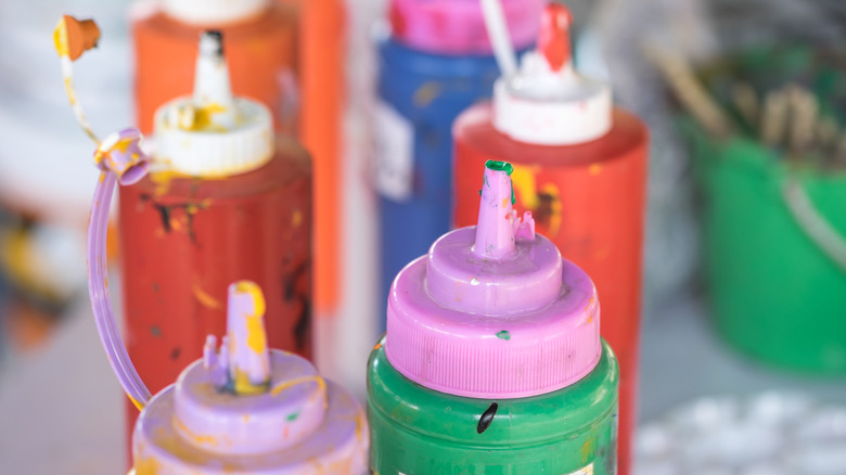 Squeeze bottles full of paint with their lids off.
