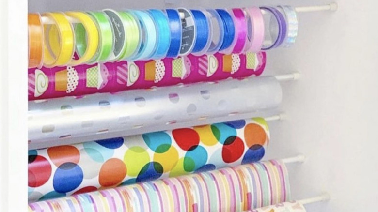 Wrapping paper stored in a cupboard using tension rods.