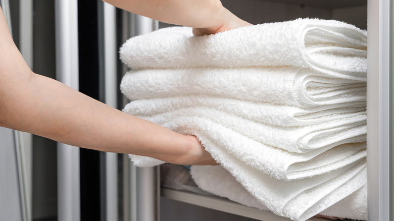 A person putting away a stack of towels