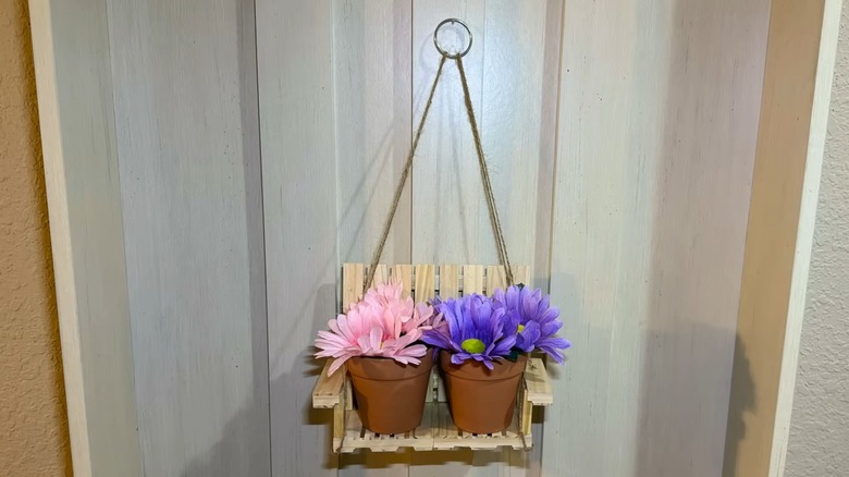 A swinging plant stand with flower-filled pots on it