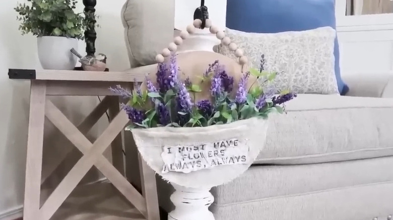 A gorgeous purple-flower filled wall hanging sign mounted on a post in a living room