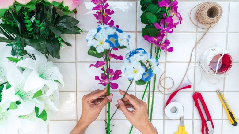 A person doing crafts with synthetic flowers