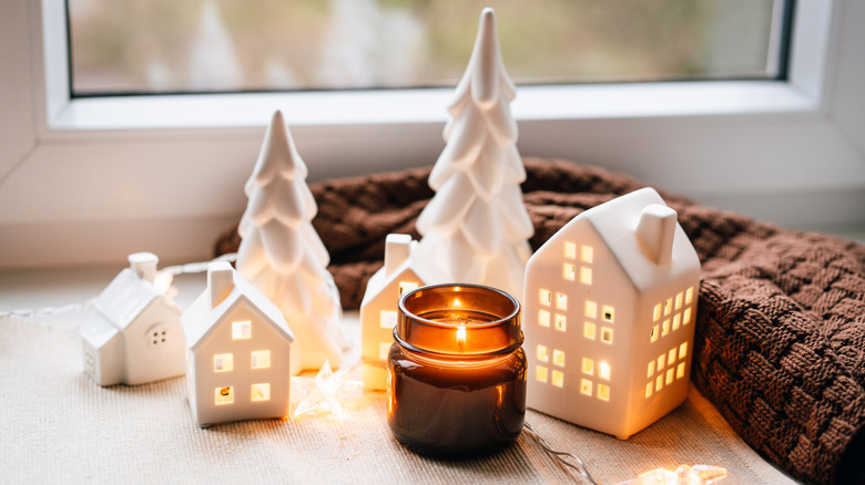 Tiny jar candle in front of ceramic decorations on a table