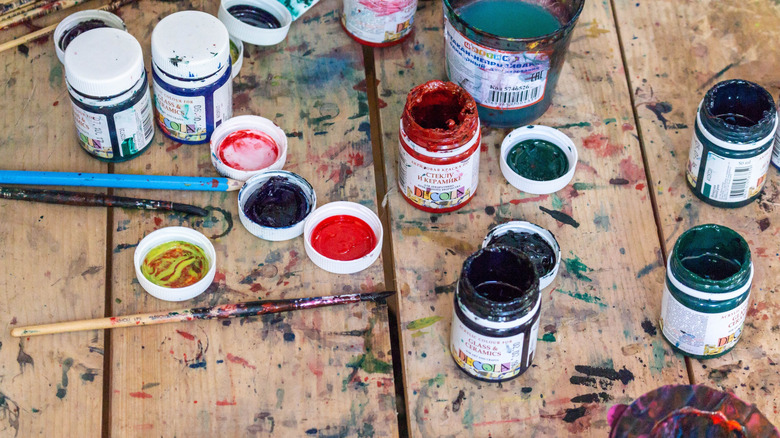 Empty acrylic pant jars with paint marks of different colors on a wooden table