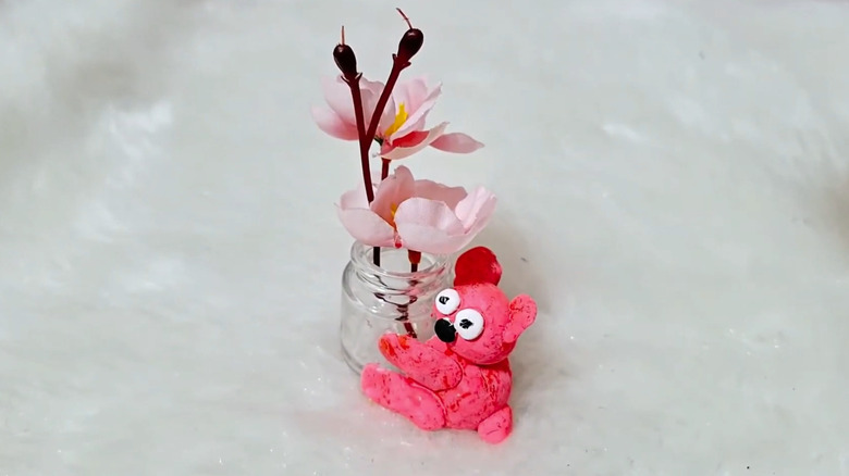 Tiny pink bear sculpture holding tiny jar