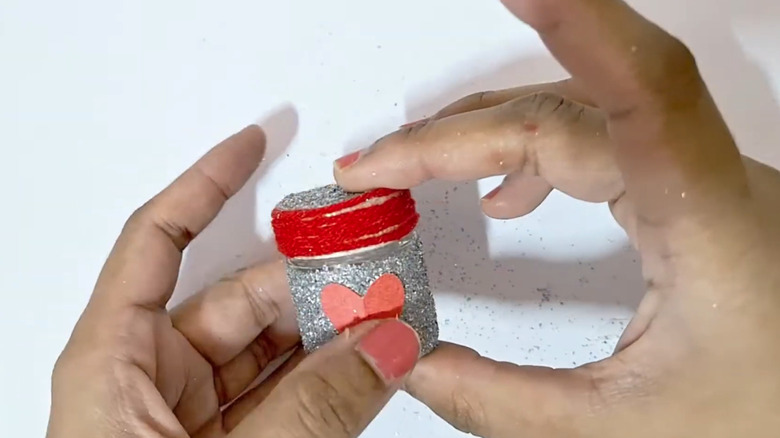 Hands holding a glittery jar with a red lid