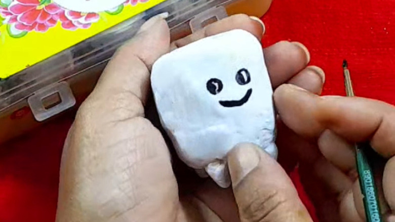 Hands holding a tiny painted tooth