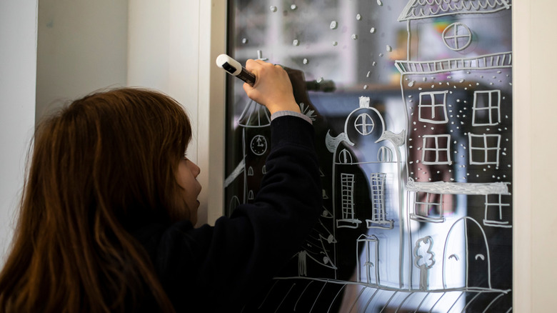 Girl drawing on the window with a chalk pen