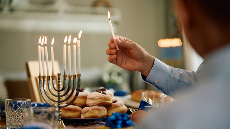 Person lighting menorah on table