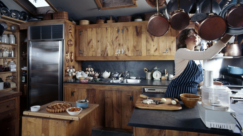 Martha Stewart reaching for pot rack in her rustic kitchen