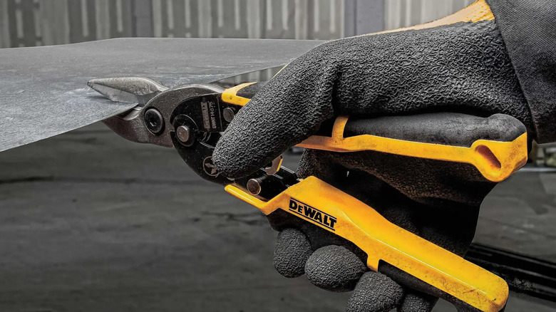 Close-up of a person cutting metal with DeWalt's 10.1-inch Straight-Cut Aviation Snips