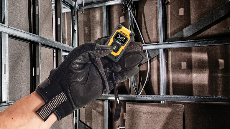 Close-up of a gloved hand holding DeWalt's 55 feet Pocket Laser Distance Measurer
