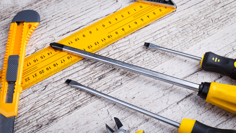 A variety of black and yellow hand tools on a wooden table