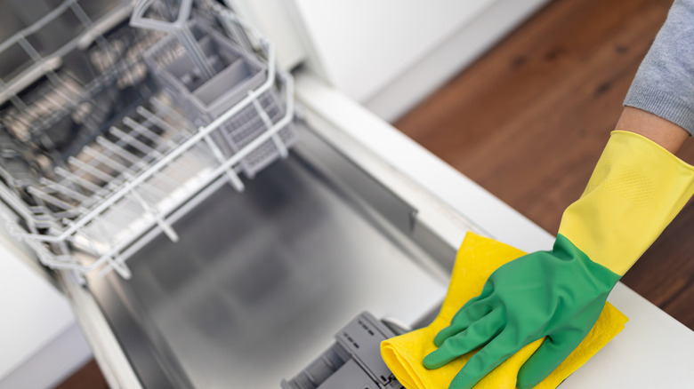 Close up of person wiping down and cleaning inside of dishwasher