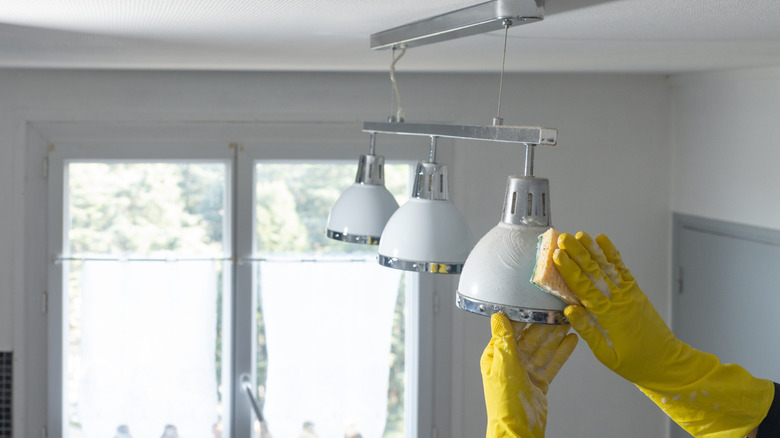 Person with gloves on cleaning kitchen light