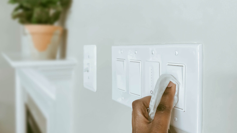Close up of woman's hand cleaning a light switch