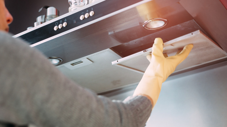 Woman removing range hood from stovetop