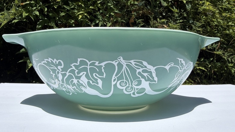 Dark green pyrex bowl with a white pattern known as Fruit Salad