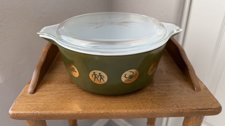 A rare Pyrex zodiac dish sits on a small wooden display table