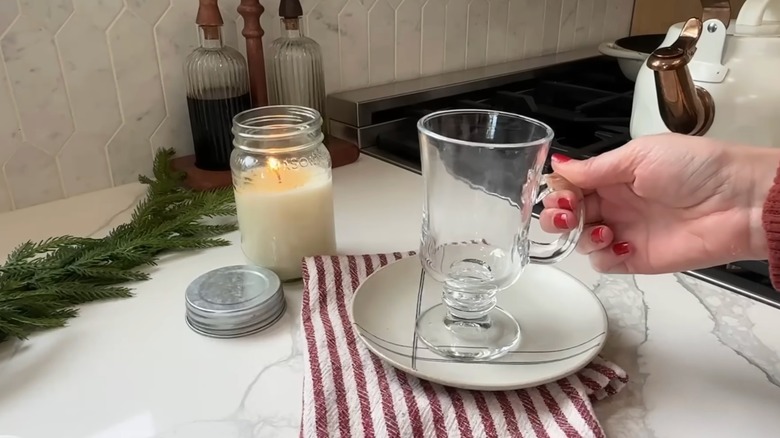 Screenshot of a YouTube video, showing a person's hand holding an empty glass Irish coffee mug.