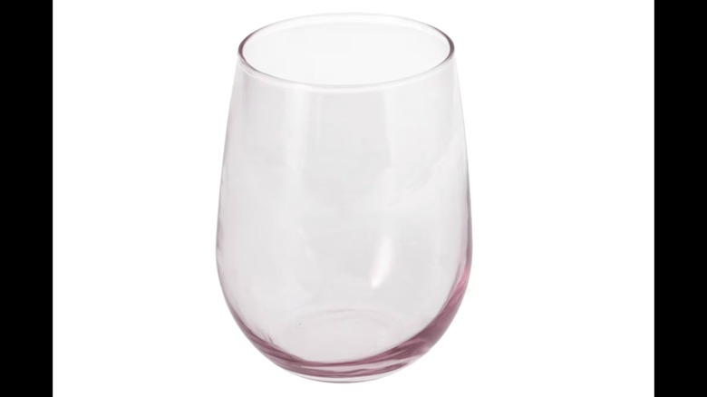 Image of a pink stained stemless wine glass against a white background.