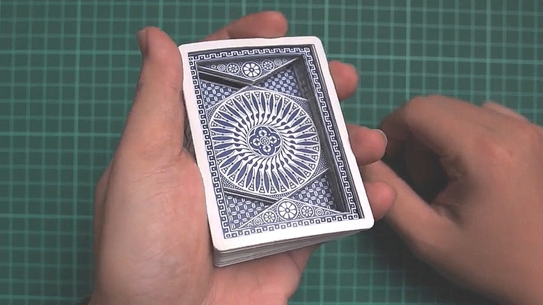 Person holding a stack of carved playing cards