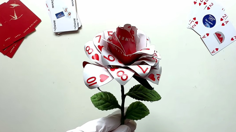 Creator holding a playing card rose with additional playing cards in the background