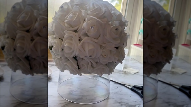 White rose boquet over a clear base on a counter in natural light