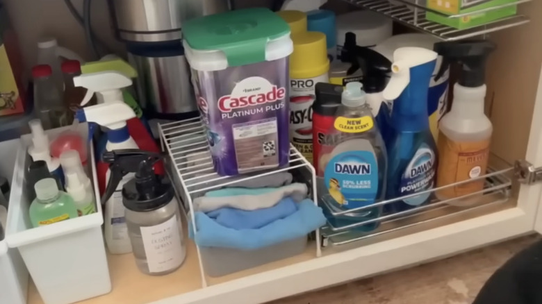 Screenshot of a Youtube video showing how to organize cabinet space under a kitchen sink.
