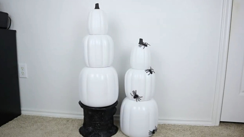 Stack of white plastic pumpkins covered with plastic spiders