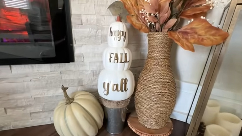 Pumpkins painted white with "Happy Fall Y'all" on them surrounded by fall decor