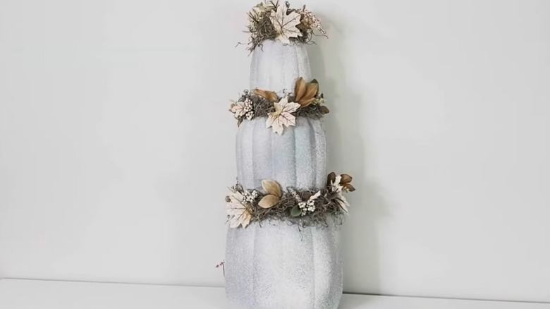Stack of plastic pumpkins that are coated with a texture stone spray and accented with florals