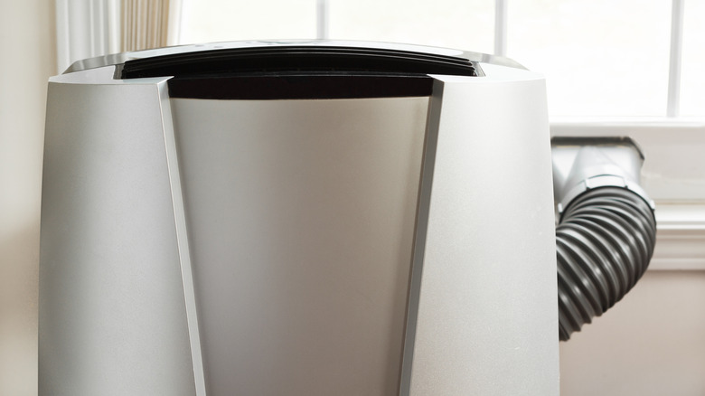 Exhaust kit installed in a window behind a large, heavy portable air conditioner