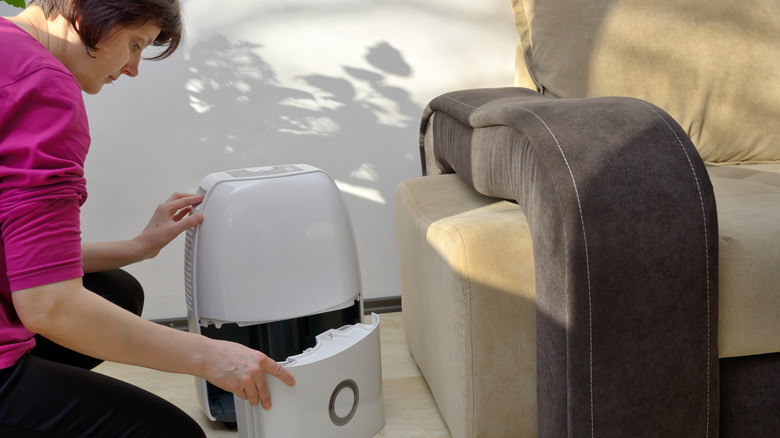 Woman checking the reservoir on a portable air condition in living room