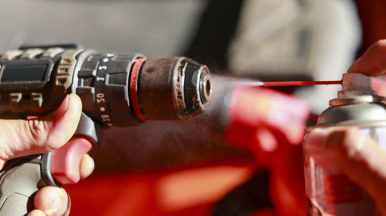 Person cleaning a drill chuck with a can of gentle air
