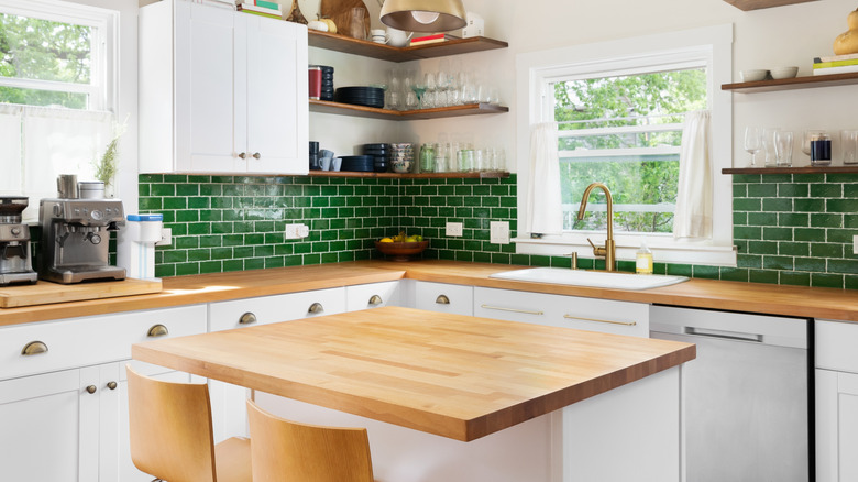 A green kitchen with a butcher block counter.