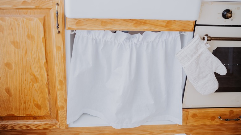 A white curtain over a cabinet or appliance.