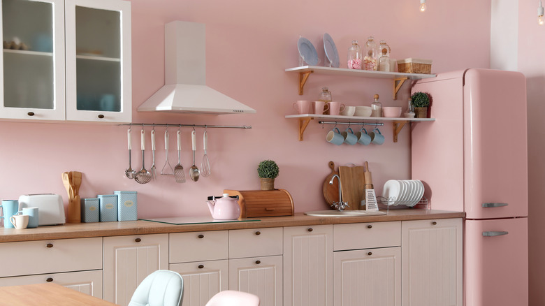 A pink and white modern kitchen with blue accents.