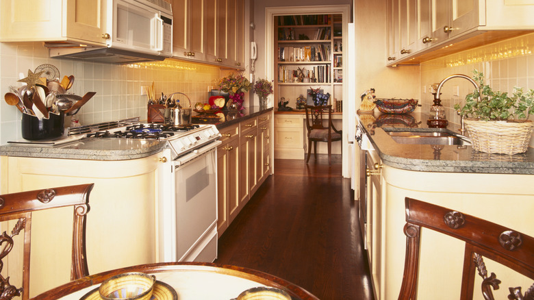 A vintage '90s kitchen with white appliances and wood furniture.